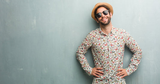 A man wearing a hat and sunglasses poses confidently for the camera, showcasing summer fashion essentials.