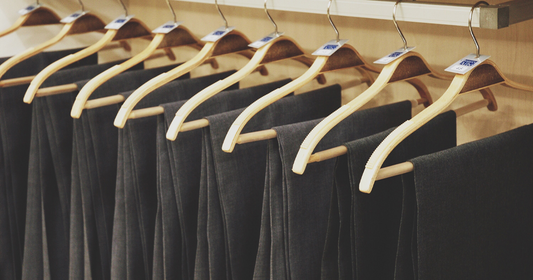  A rack displaying several pairs of black pants neatly hanging on hangers, illustrating men's pant sizes.